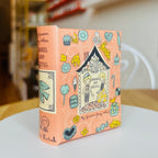 Decorative book style case with colorful illustrations of Hansel and Gretal on a white surface