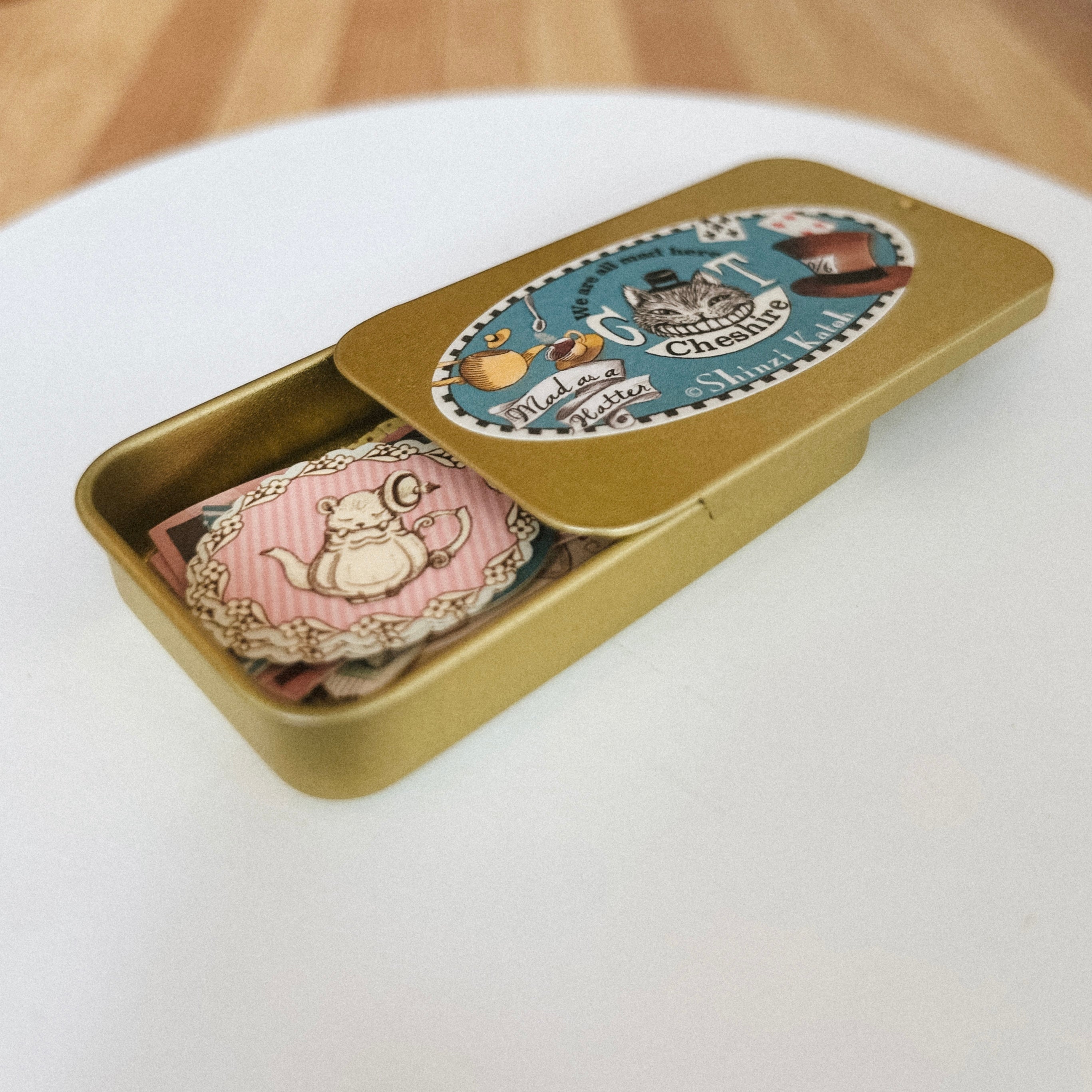 Gold tin with Japanese flake stickers and decorative label on a white surface