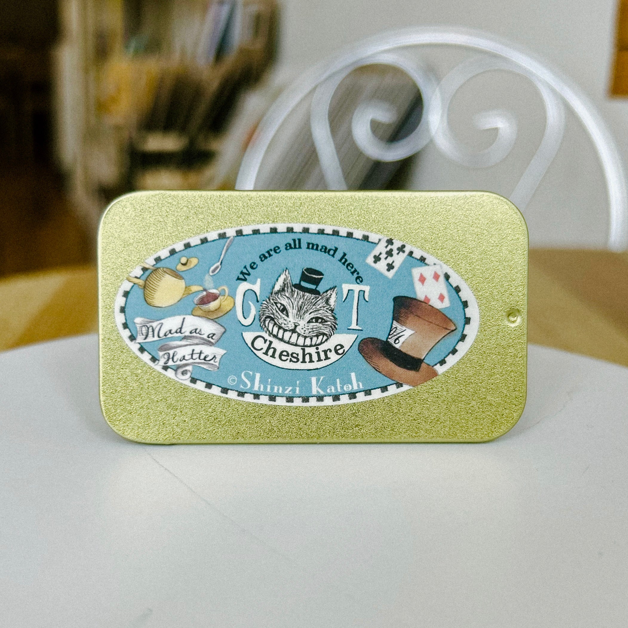 Decorative tin with Cheshire Cat design on a white surface
