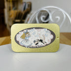 Decorative tin with illustrations of Alice and a rabbit on a gold background