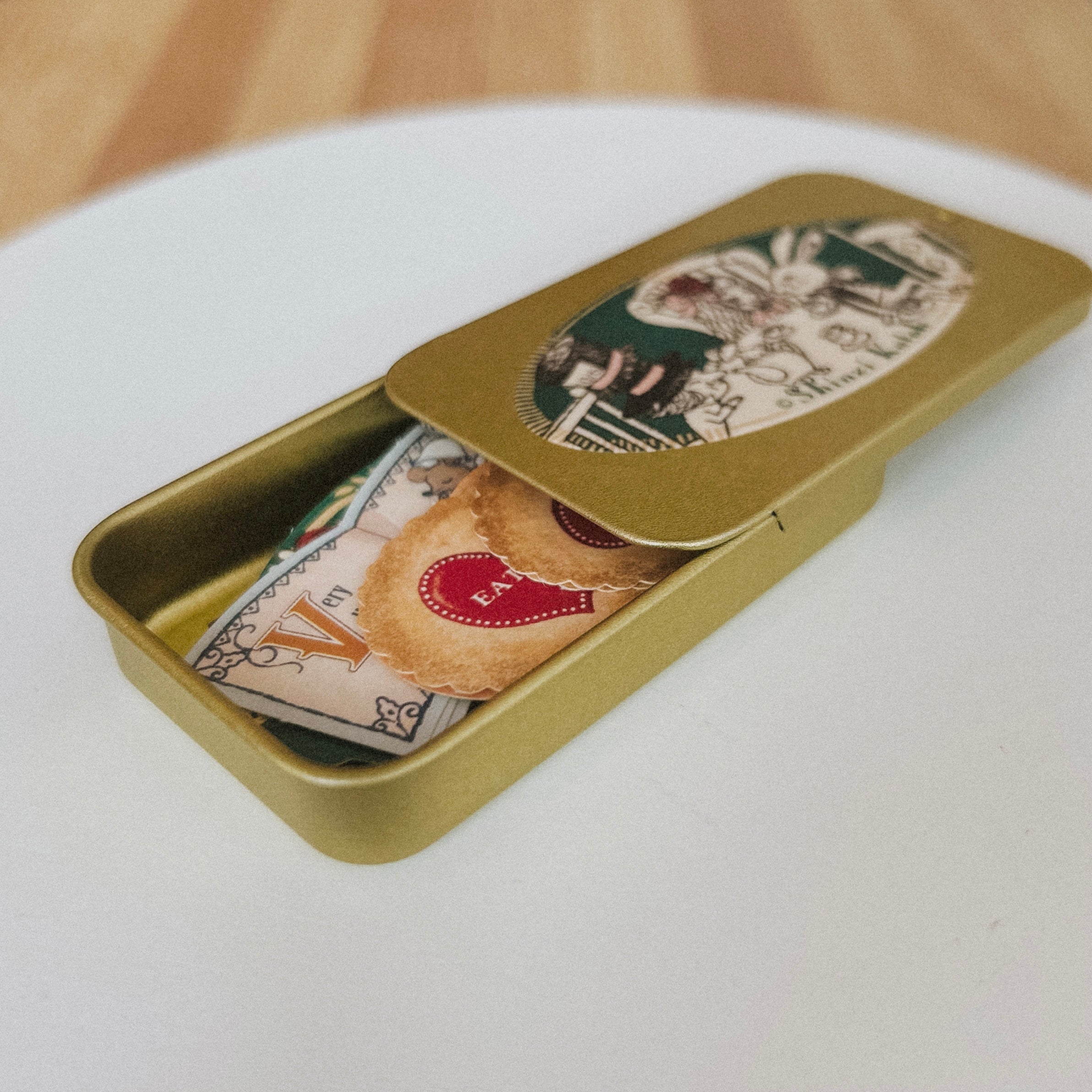 Gold tin box with Japanese stickers on a white surface