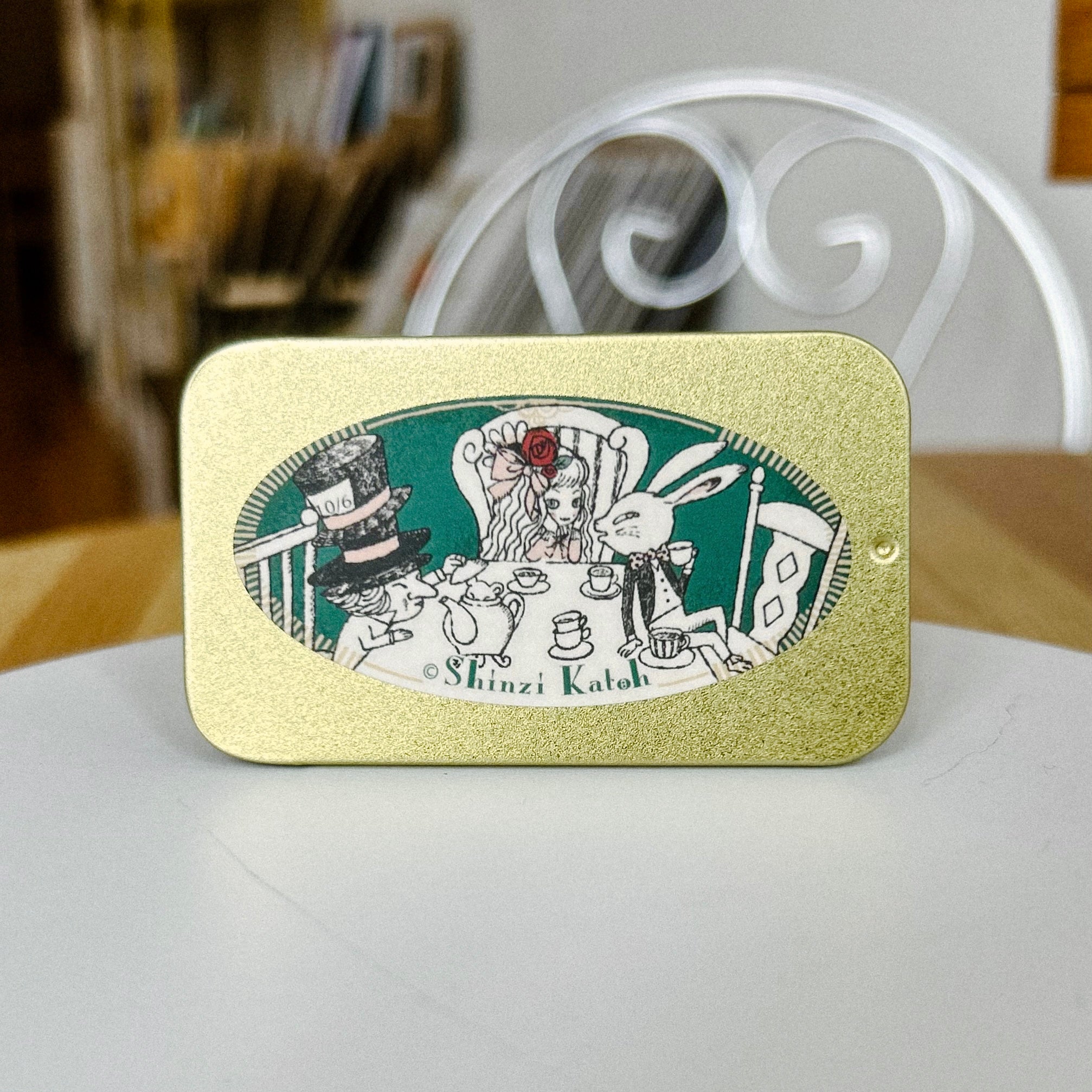 Decorative tin with a design of characters such as rabbit, Alice, and Mad Hatter having a tea party